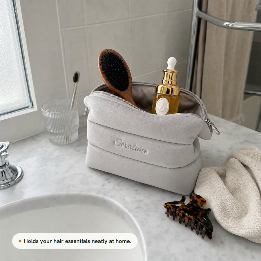 Puffy Beauty Bag open on a bathroom counter with Lumina Oil and the AirTouch Brush