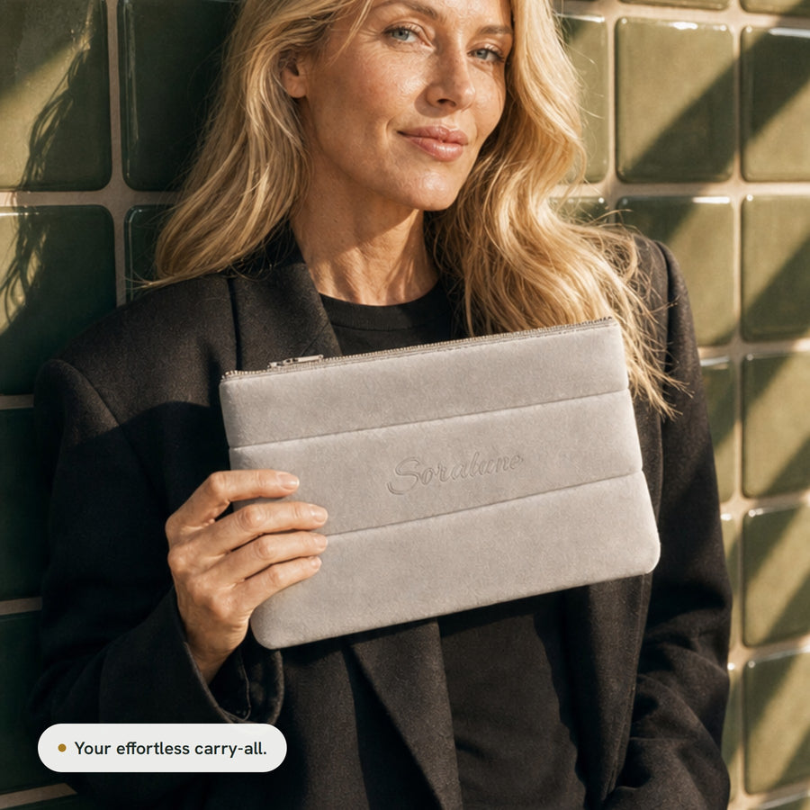 A woman in a black blazer holding the Puffy Beauty Bag