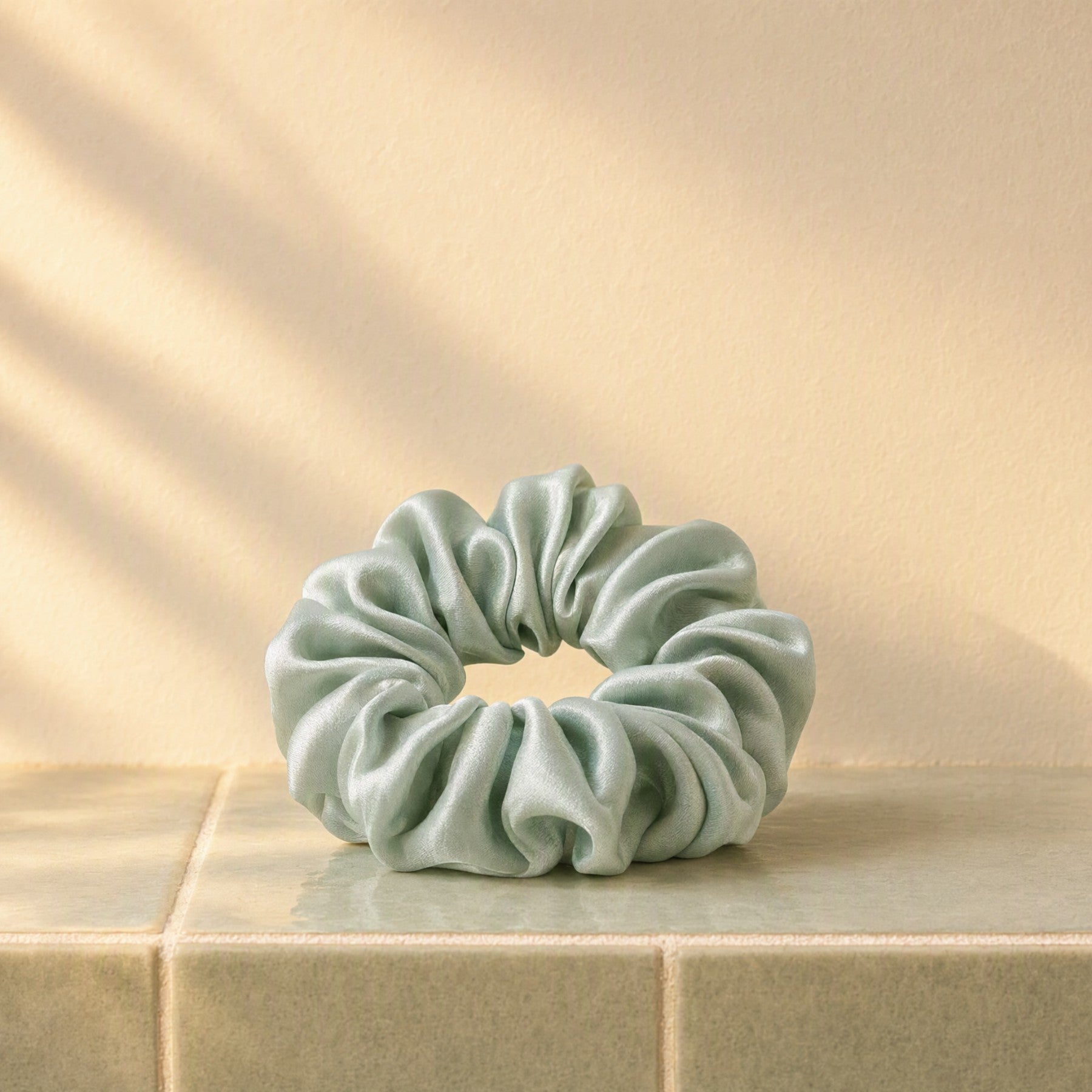 Hero and order-box tile: the sage silk scrunchie in warm light, no words