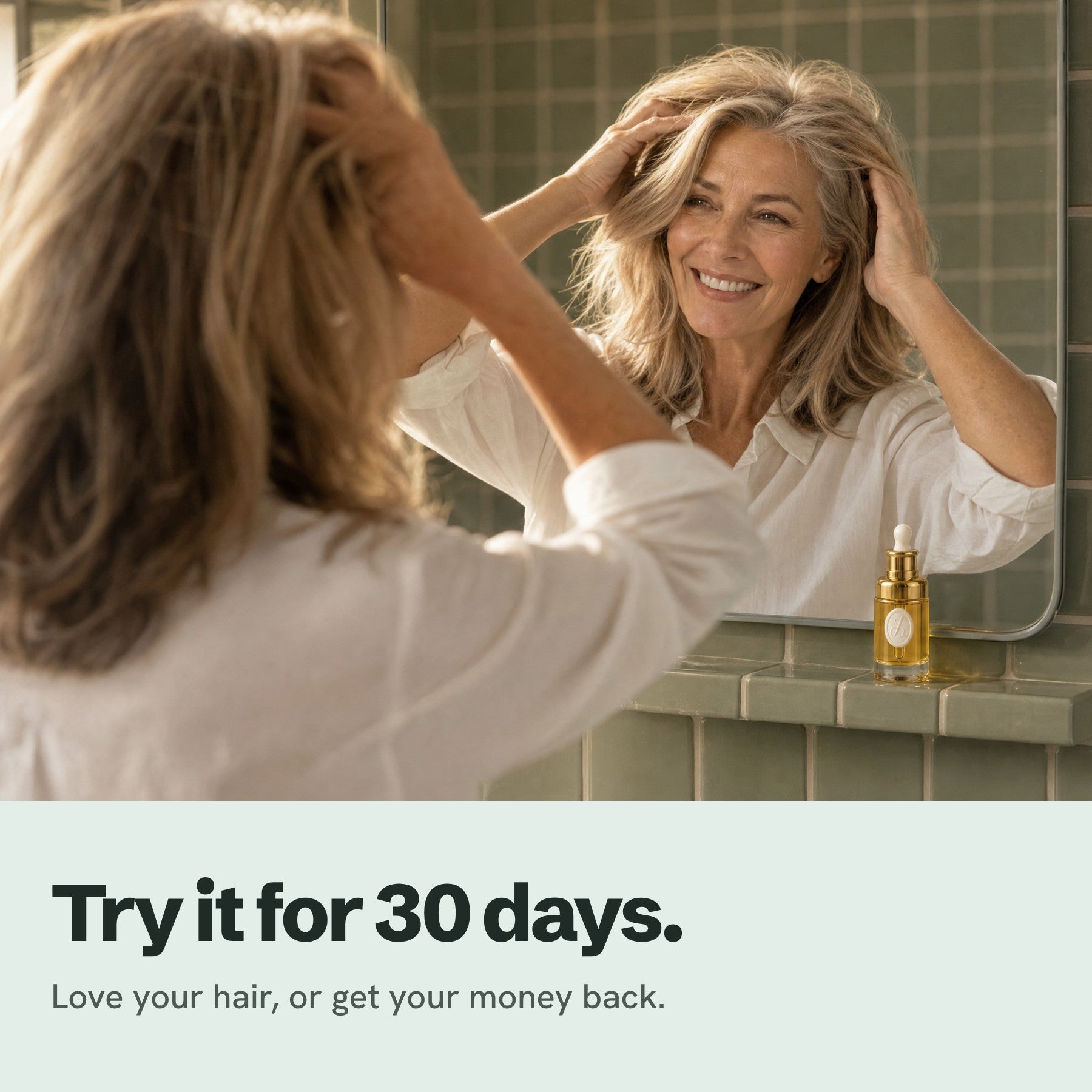 Try it for 30 days: a woman smiling at her hair in the mirror